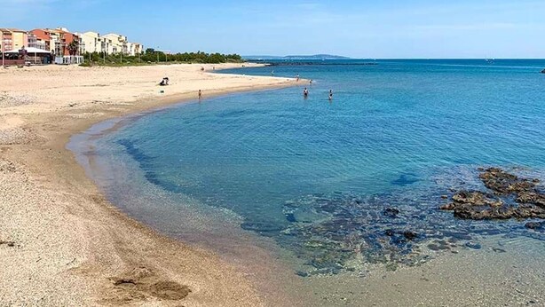 A beach with clear water, a sandy shore, and buildings in the background. - Studio with AC and pool - 4 guests (Cap d'Agde)