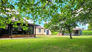 Une maison avec un patio couvert, une pelouse et un arbre.