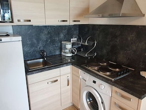 A compact kitchen with a washing machine, a coffee maker, and a built-in oven. - Apartment sea view, parking - 6 guests (Cap d'Agde)