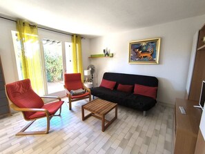 Ein Wohnzimmer mit einer Couch, zwei Sesseln, einem Couchtisch und einem Bild an der Wand.