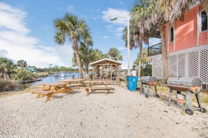 Un espace aménagé au bord de la plage, avec des tables de pique-nique, un barbecue et un petit pavillon.