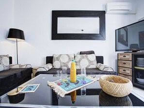 A modern living room with a sofa, a coffee table, a lamp, and a television. - Apartment with air conditioning - 4 guests (Cap d'Agde)
