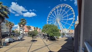 A Ferris wheel, palm trees, and a building with a sign. - Studio with port view - 2 guests (Cap d'Agde)