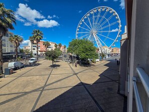 A Ferris wheel, palm trees, and a building with a sign. - Studio with port view - 2 guests (Cap d'Agde)