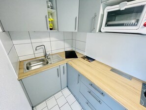 Eine kleine Küche mit Spüle, Schränken und einer Mikrowelle.
