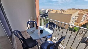 Ein Balkon mit Tisch und Stühlen, Blick auf Gebäude und einem klaren Himmel.