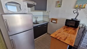 Eine kleine Küche mit Kühlschrank, Mikrowelle, Spüle und Holzarbeitsplatte.