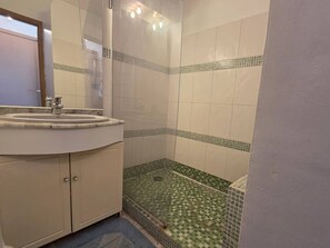 Ein Badezimmer mit Waschbecken, Spiegel und Duschbereich.