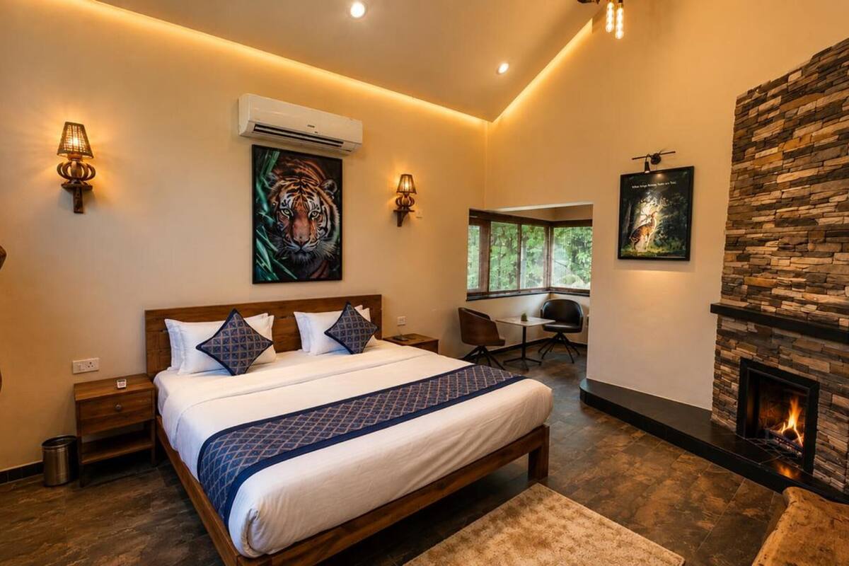 A bedroom with a bed, a stone fireplace, and artwork on the walls.