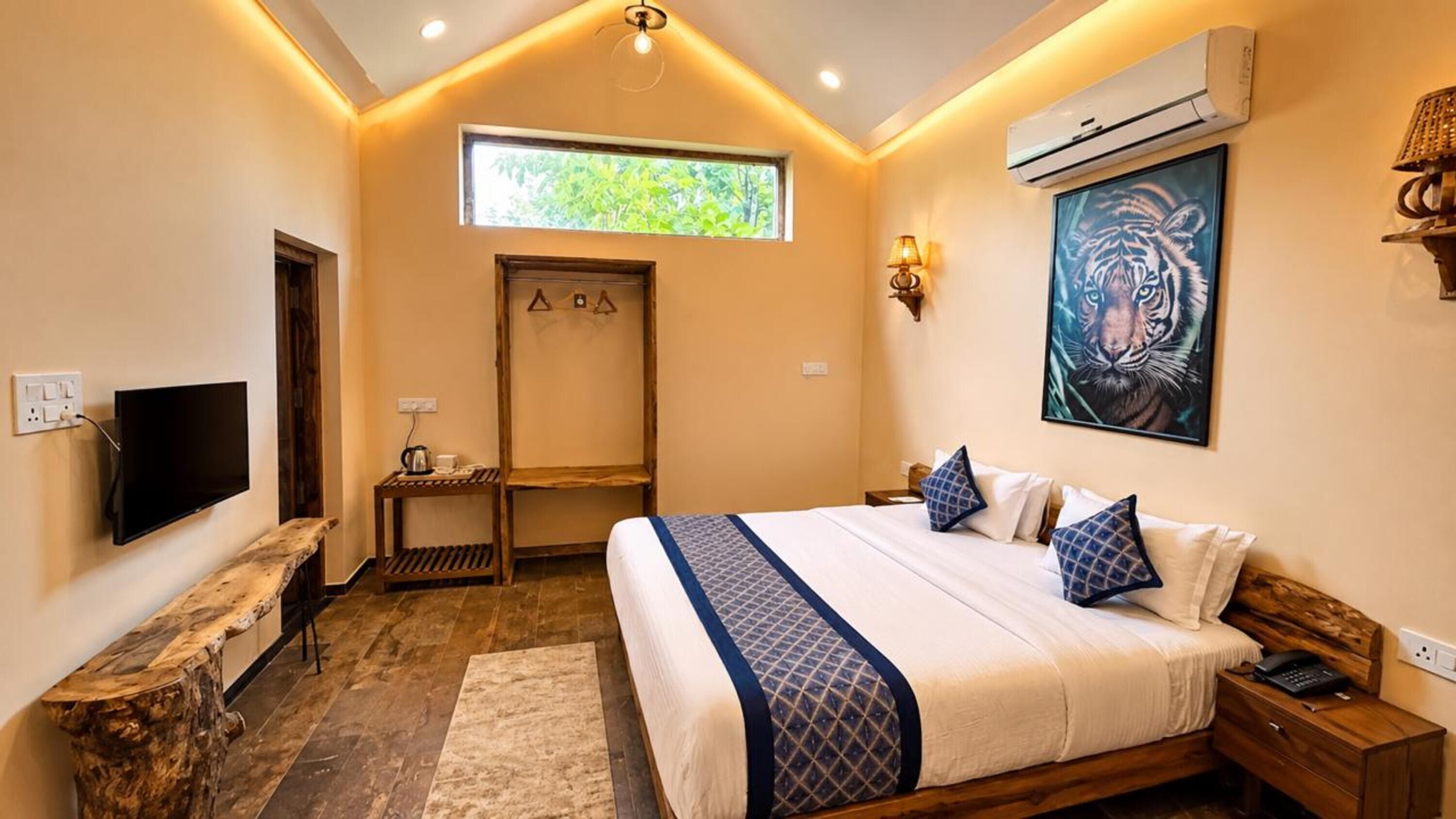 A bedroom with a bed, bedside table, TV, and a window.
