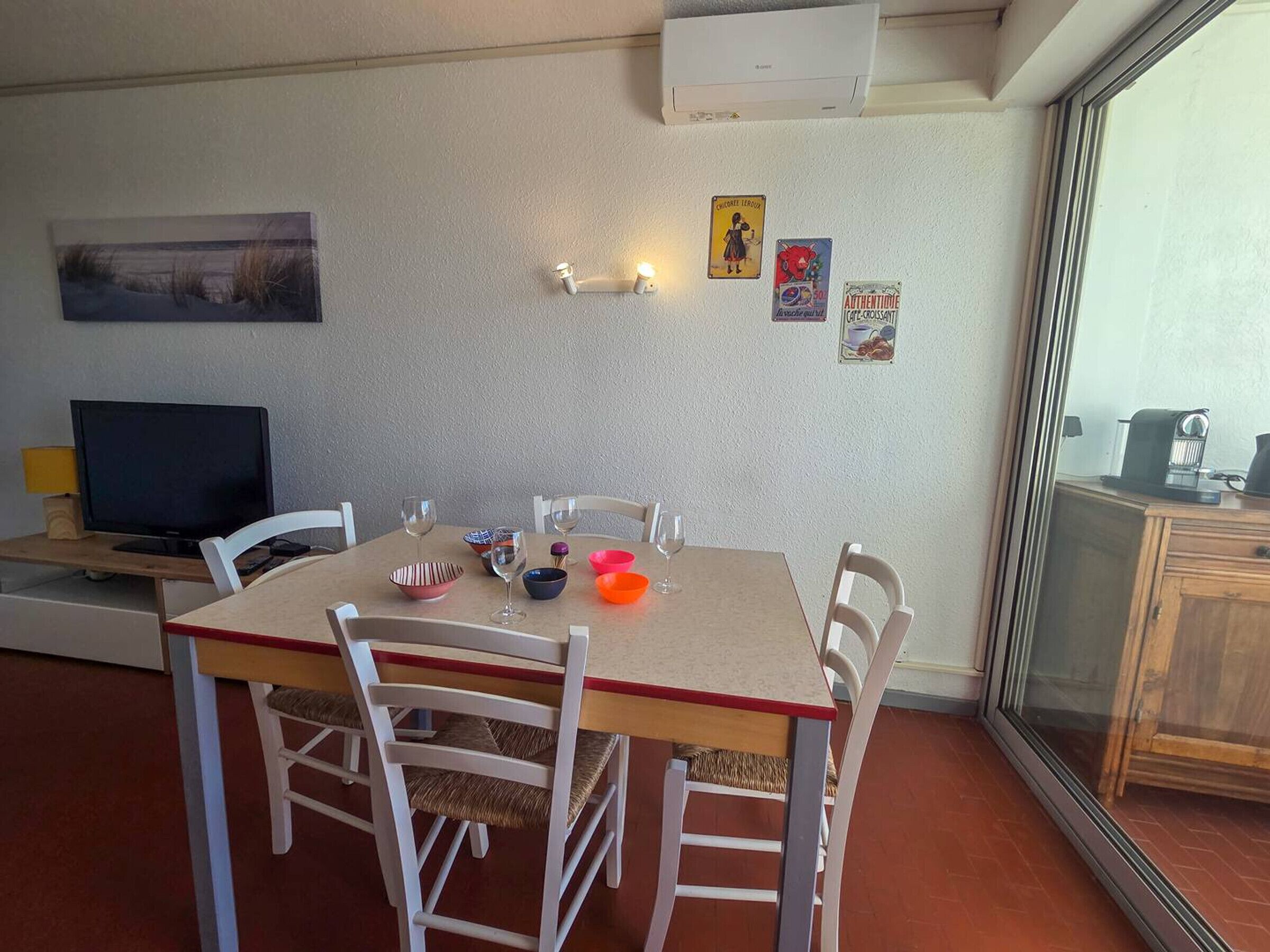 A dining area with a table, chairs, and a television.