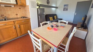 A compact kitchen with a dining table, chairs, a refrigerator, and a microwave. - Air-conditioned apartment at the port - 4 guests (Cap d'Agde)