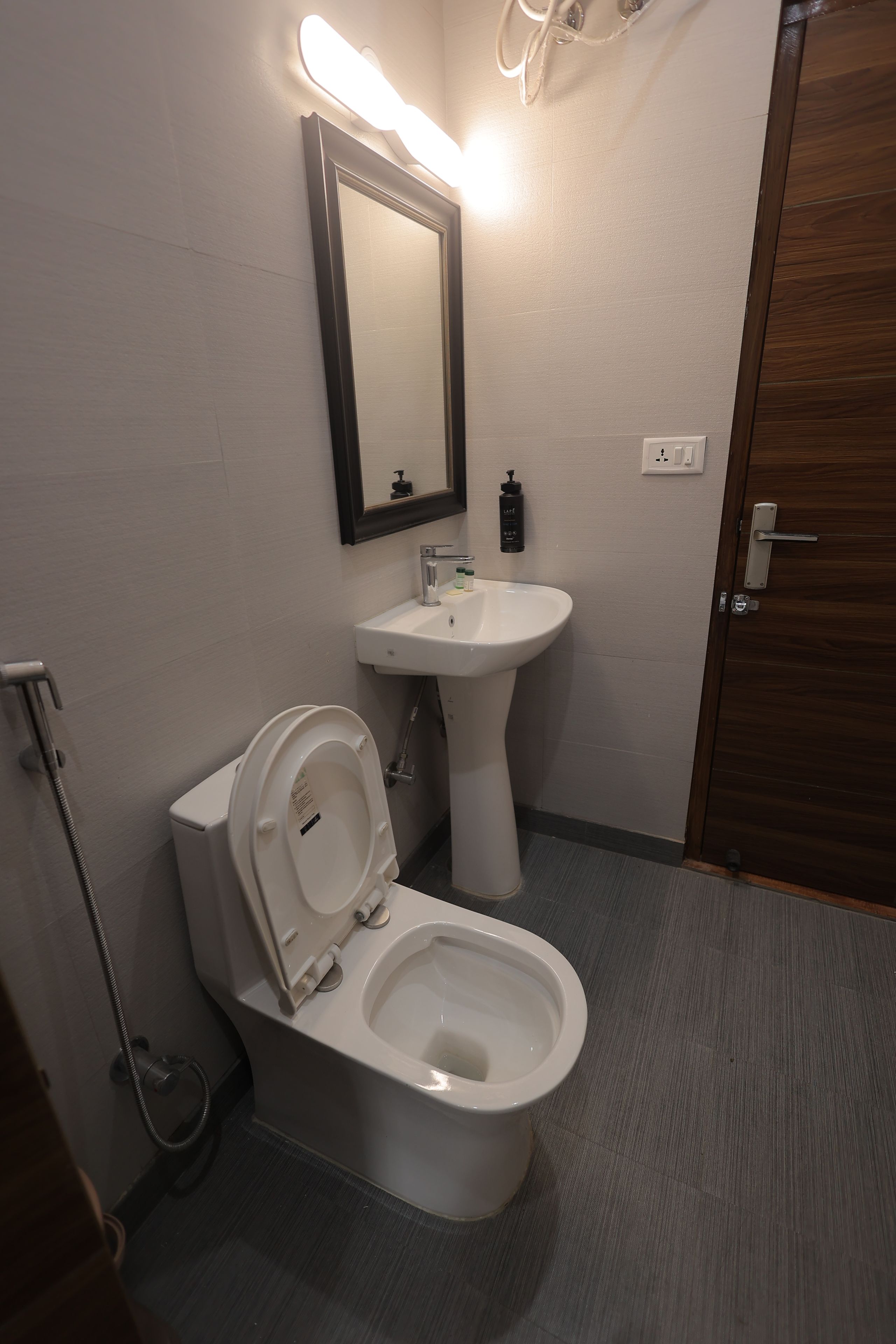 A bathroom with a toilet, sink, and mirror.