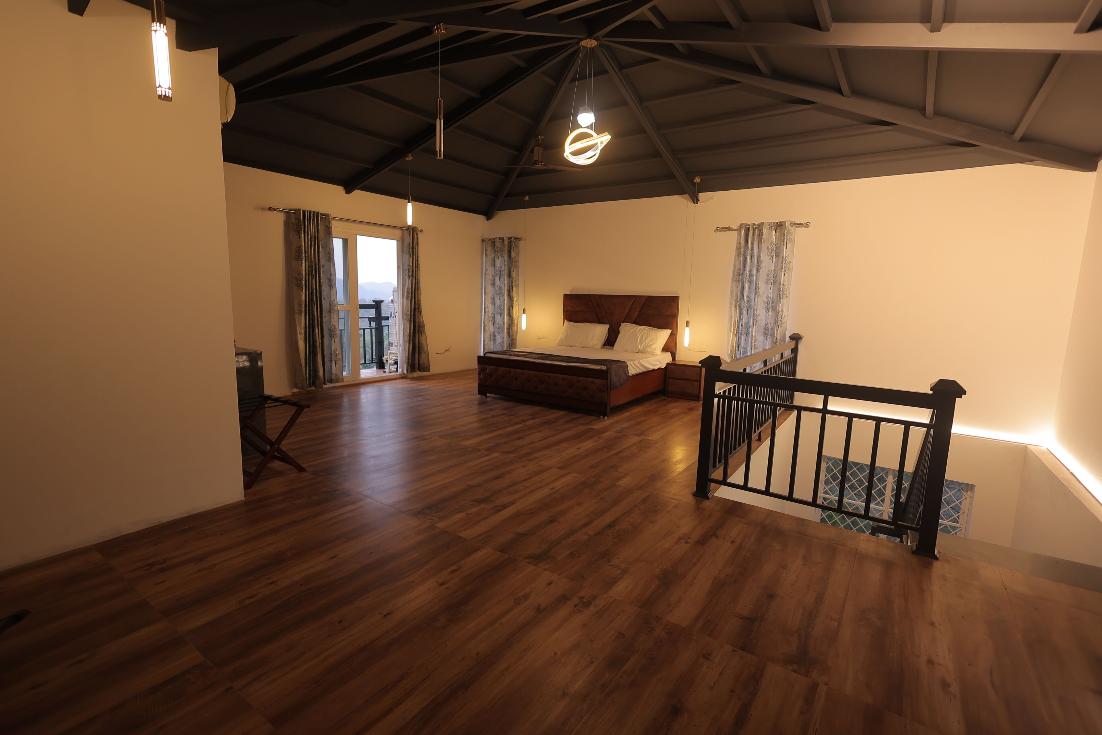 Ein geräumiges Schlafzimmer mit Holzboden, einem großen Bett, einem Deckenventilator und einer Treppe.
