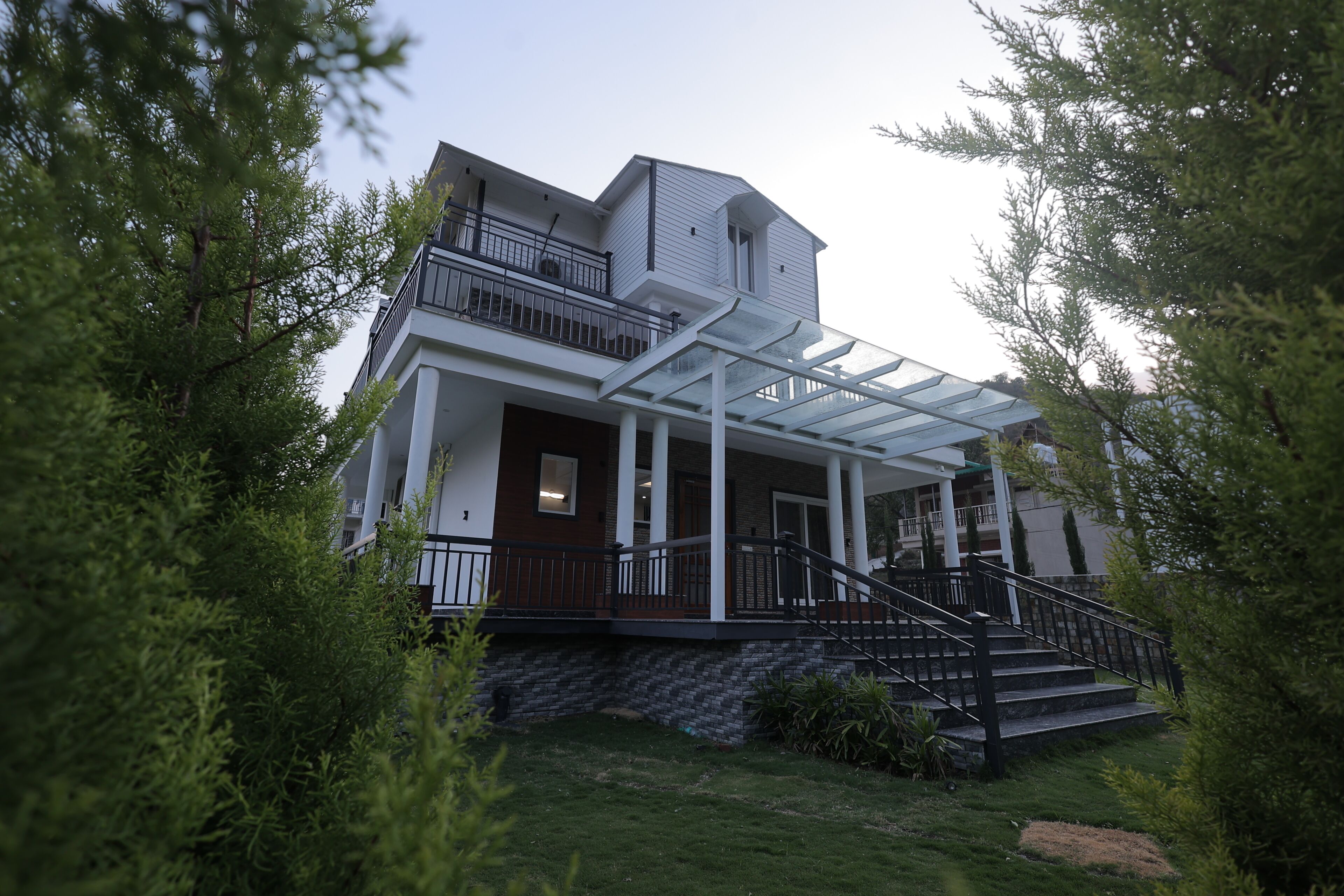 A two-story house with a covered porch, a staircase, and a small garden area.