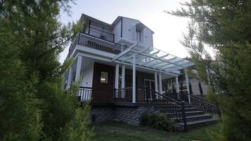 A two-story house with a covered porch, a staircase, and a small garden area.