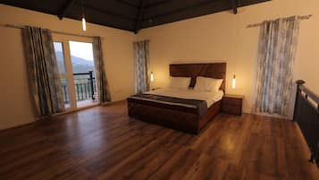 Un dormitorio amplio con una cama grande, piso de madera y vistas al balcón.