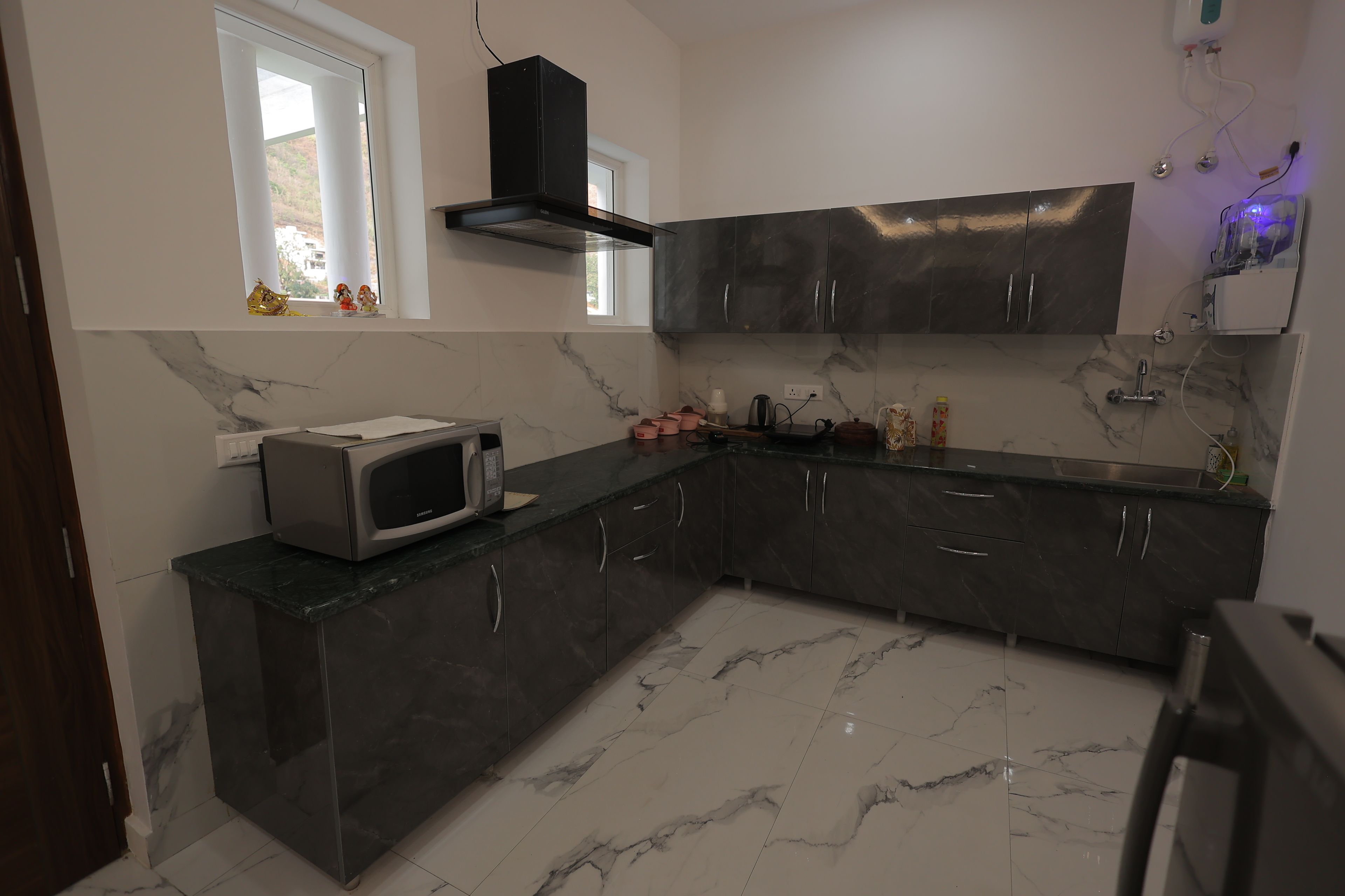 Cocina moderna con armarios oscuros, un microondas y una ventana decorada.