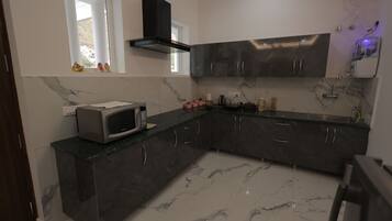 Cocina moderna con armarios oscuros, un microondas y una ventana decorada.