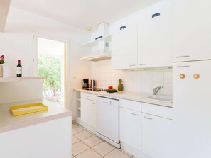 A modern kitchen with white cabinets, a coffee maker, and a pineapple on the counter. - Superior Villa for 4 People With Swimming Pool (Lacanau)