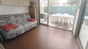 Una stanza con un divano, un tavolo, sedie e una porta vetrata scorrevole che dà su uno spazio all'aperto.