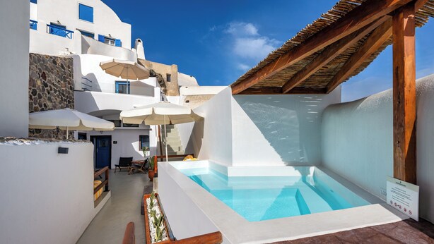 A pool area with a wooden pergola, white walls, and a clear blue sky. - Orasis Houses- Luxury Retreats with Pool (Akrotiri)