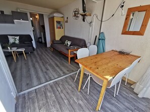 A compact living space with a wooden dining table, two sofas, a small white table, and a staircase leading to another room. - Studio cabin, parking, sea view - 5 guests (Cap d'Agde)