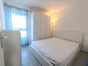A bedroom with a bed, a wardrobe, a desk, and a lamp. - Apartment with port view - 6 guests (Cap d'Agde)