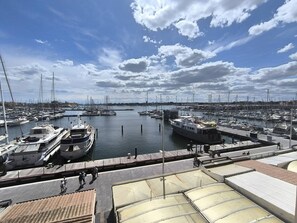 A marina with boats docked, a clear sky, and a distant shoreline. - Apartment with port view - 6 guests (Cap d'Agde)