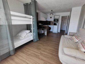 Ein kompakter Wohnbereich mit Etagenbett, Küchenzeile und Schlafsofa.