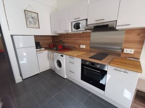 Eine moderne Küche mit Waschmaschine, Backofen, Mikrowelle und Kaffeemaschine.