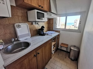 Eine kleine Küche mit Spüle, Mikrowelle, Wasserkocher und einem Fenster mit Blick.