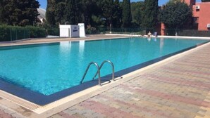 A swimming pool with a tiled deck, surrounded by trees and a building. - Studio with parking, quiet and near beach - 4 guests (Cap d'Agde)