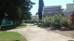 A residential area with a paved driveway, greenery, and a building with a tiled roof. - Studio with parking, quiet and near beach - 4 guests (Cap d'Agde)