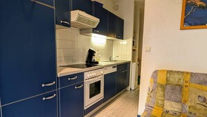 A compact kitchen with blue cabinets, a stove, a dishwasher, and a tiled backsplash. - Studio with parking, quiet and near beach - 4 guests (Cap d'Agde)