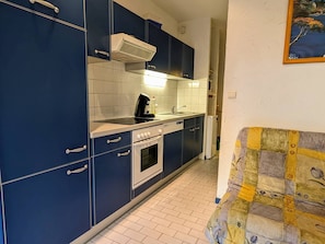 A compact kitchen with blue cabinets, a stove, a dishwasher, and a tiled backsplash. - Studio with parking, quiet and near beach - 4 guests (Cap d'Agde)