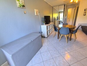 Ein kompakter Wohnbereich mit einer Couch, einem Esstisch mit Stühlen, einem Fernseher und einem Schrank.