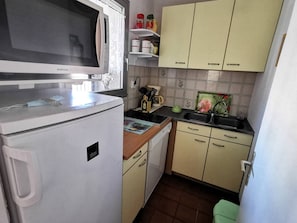 Eine kleine Küche mit Mikrowelle, Kühlschrank, Spüle und Schränken.