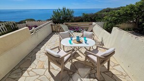 A patio with a table and chairs, a view of the sea, and a stone floor. - Studio cabin sea view, parking - 4 guests (Cap d'Agde)