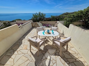 A patio with a table and chairs, a view of the sea, and a stone floor. - Studio cabin sea view, parking - 4 guests (Cap d'Agde)