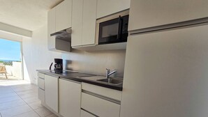 A modern kitchen with white cabinets, a stainless steel countertop, a built-in microwave, and a coffee maker. - Studio cabin sea view, parking - 4 guests (Cap d'Agde)
