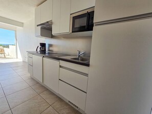 A modern kitchen with white cabinets, a stainless steel countertop, a built-in microwave, and a coffee maker. - Studio cabin sea view, parking - 4 guests (Cap d'Agde)