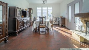 Comedor con una mesa dispuesta para cuatro personas, rodeada de sillas de madera y un aparador con objetos decorativos.