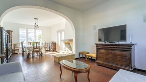 Una sala de estar amplia con chimenea, televisor y comedor con sillas y mesa.