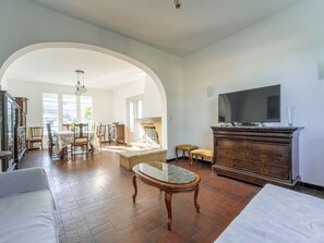 Ein geräumiges Wohnzimmer mit Kamin, Fernseher und Essbereich mit Stühlen und Tisch.