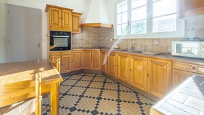 Una cocina con armarios de madera, piso de baldosas y una ventana.