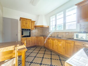 Eine Küche mit Holzausstattung, Fliesenboden und einem Fenster.