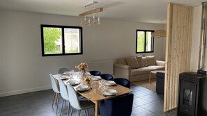 A dining area with a table set for four, a sofa, and a wood-burning stove. - Quiet & comfortable vacation home - 1500m from the beach 3 bedrooms 2 bathrooms - sleeps 7 (Dragey-Ronthon)