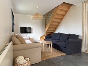 A modern living room with a sofa, a coffee table, a TV, and a staircase. - Quiet & comfortable vacation home - 1500m from the beach 3 bedrooms 2 bathrooms - sleeps 7 (Dragey-Ronthon)