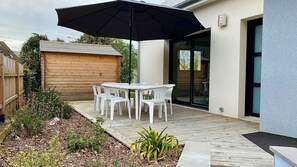 A patio with a table and chairs, an umbrella, and a wooden fence. - Quiet & comfortable vacation home - 1500m from the beach 3 bedrooms 2 bathrooms - sleeps 7 (Dragey-Ronthon)